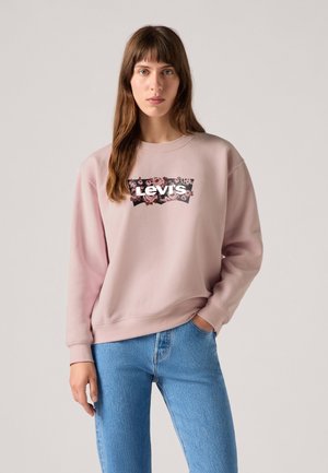 Pink sweatshirt with a crew neck, featuring a floral Levi's logo design on a black background. Paired with light blue jeans.