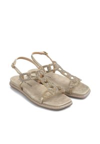 Sandales dorées à semelle plate, avec une sangle décorative ornée de strass dans un design en chaîne et une boucle réglable à la cheville.
