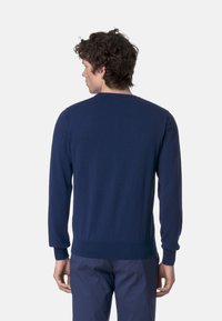 Pullover lavorato a maglia blu navy con scollo rotondo, maniche lunghe, polsini e orlo a costine. Texture liscia, design minimale e senza motivi visibili.