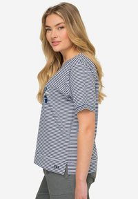 Pasiasta koszulka z krótkim rękawem w granatowo-białym kolorze, wykonana z bawełny. Posiada okrągły dekolt, boczne szczeliny oraz małe logo na dolnej krawędzi.