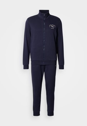 Granatowy dres z kurtką na zamek z wysokim kołnierzem i logo, w komplecie z dopasowanymi, zwężanymi spodniami, wykonanymi z miękkiego, teksturowanego materiału.
