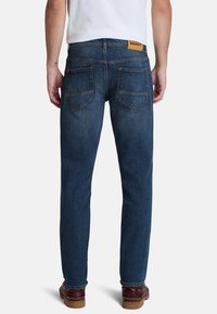 Jeans de mezclilla en azul oscuro, con un corte recto, costuras dobles, bolsillos traseros y una etiqueta de cuero con la marca en la cinturilla.