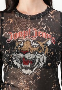 Must mustre top, millel tiigeri graafika, kaunistatud rhinestone'ide ja tekstiga "Joop! Jeans", mille taustaks on nahkhiirte muster.