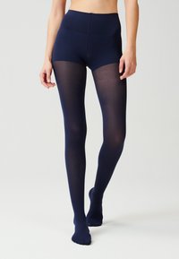 Collant blu navy con vita alta e texture trasparente, che arrivano fino ai piedi, caratterizzati da una finitura liscia e senza cuciture visibili.