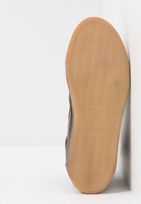 Chaussure noire avec semelle en gomme, surface texturée et profil élégant. Présente l'étiquette de taille '41' sur la semelle.