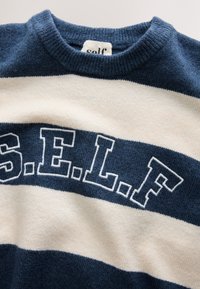 Jersey de punto a rayas azul marino y blanco con la palabra "S.E.L.F." tejida en el pecho con grandes letras en bloque.