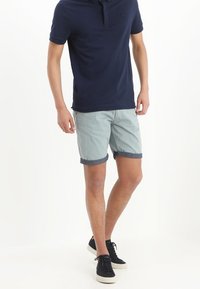 Navy polo shirt, light blue shorts with rolled hem, and black sneakers. Comfy fabric with classic fit and simple design.