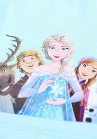 Tissu bleu clair présentant des personnages de dessin animé de La Reine des Neiges : Elsa, Kristoff, Anna et Sven, avec Elsa tenant un flocon de neige lumineux.