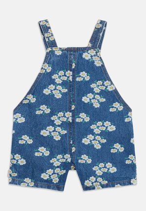 Denim short overalls with adjustable straps, featuring a white daisy flower print with green leaves on blue fabric.