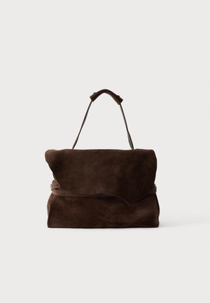 Borsa in pelle scamosciata marrone scuro con patta asimmetrica e singolo manico superiore su sfondo semplice.