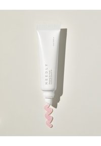 Hvit klemrør med ribbet hette, merket "NEEDLY Sleeping Lip Mask." Rosa, blankt produkt sirkler fra åpningen mot en lys bakgrunn.