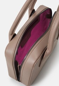 Beige läderhandväska med dubbla handtag och rosa inredning. Har ett dragkedjestängning och en slät yta med ett innerfack.
