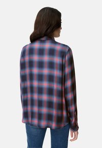 Long-sleeve plaid shirt in navy blue and red tones. Soft fabric with a smooth texture. Features a buttoned cuff and a curved hem.