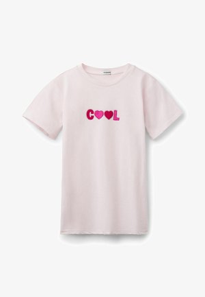 T-shirt rose clair à manches courtes avec "COOL" en lettres épaisses, où les deux O sont remplacés par des formes de cœur roses.