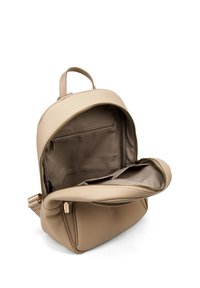 Zaino in pelle beige con design arrotondato, che presenta un compartimento principale con cerniera e una tasca interna, texture liscia e dettagli minimalisti.