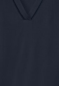 Top blu navy a V realizzato in tessuto morbido, con un bordo testurizzato lungo il collo. Design semplice con una superficie liscia.