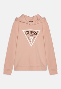 Felpa rosa chiaro con un logo triangolare bianco sul davanti che recita "GUESS U.S.A." e "Washed Jeans" attorno a un punto interrogativo.