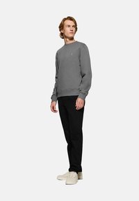 Grå crewneck sweatshirt i mjukt material med ribbstickade muddar och nederkant. Bärs med svarta byxor och ljusa sneakers.