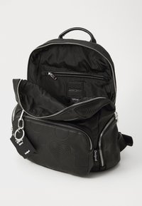 Zaino nero realizzato in nylon e pelle texturizzata, dotato di vari scomparti con cerniera, motivi in rilievo e un'etichetta con il logo.