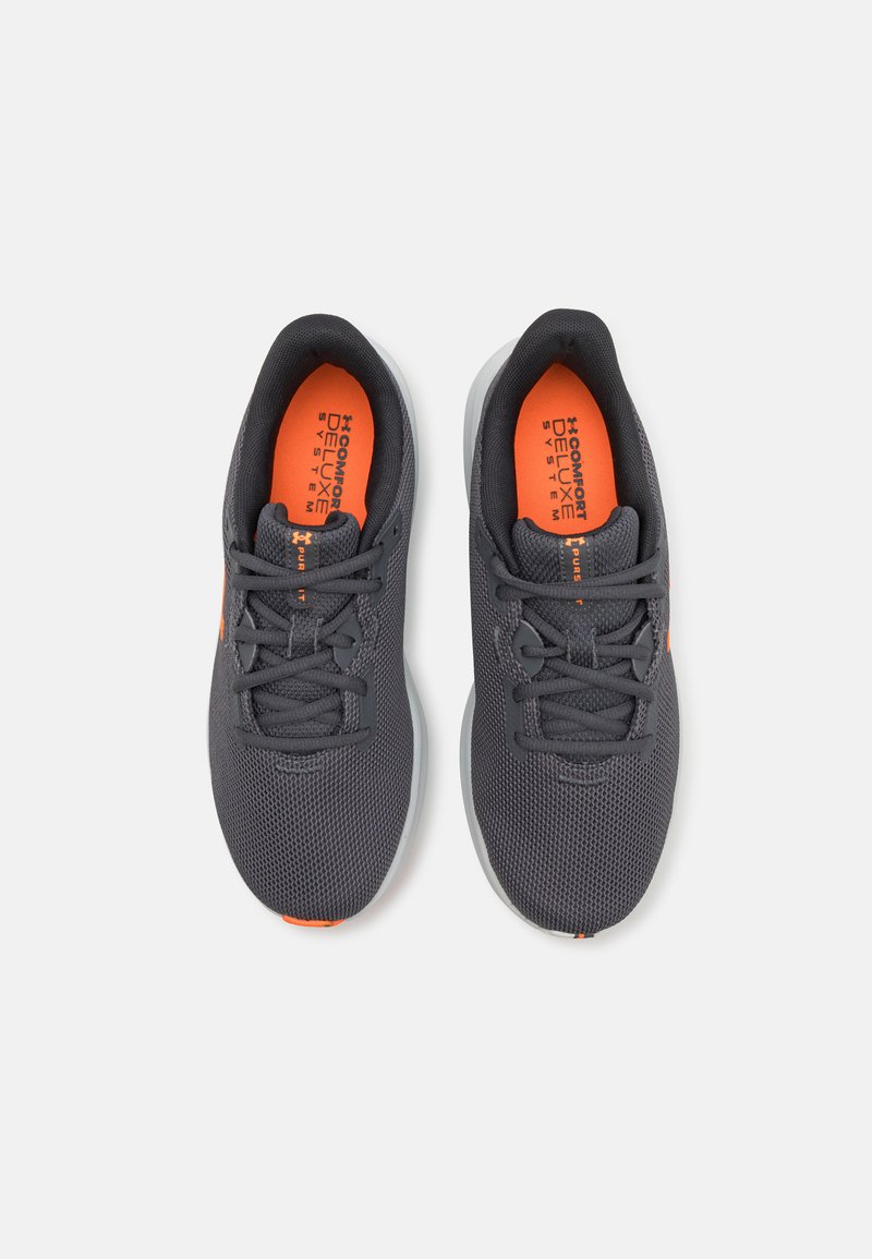 Baskets de sport gris foncé avec une tige en mesh respirant, accent orange sur la languette et semelle blanche rembourrée. Présente un système de laçage standard.