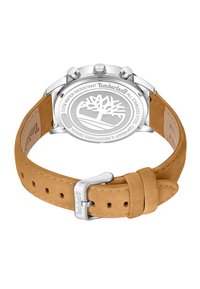 Timberland pulksteņa sudraba nerūsējošā tērauda korpuss, brūnas ādas siksna un iegravēts logo uz aizmugurējā korpusa; apaļa forma ar gludu apdari.