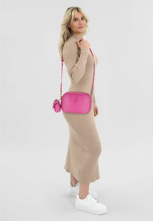 Blonde woman wearing a beige ribbed long dress and white sneakers, carrying a quilted pink crossbody bag with a small pouch attached.