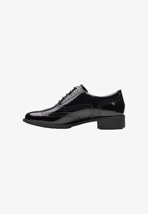 Black patent leather oxford shoe with brogue detailing, rounded toe, and a low heel. Features a smooth surface and intricate perforations.