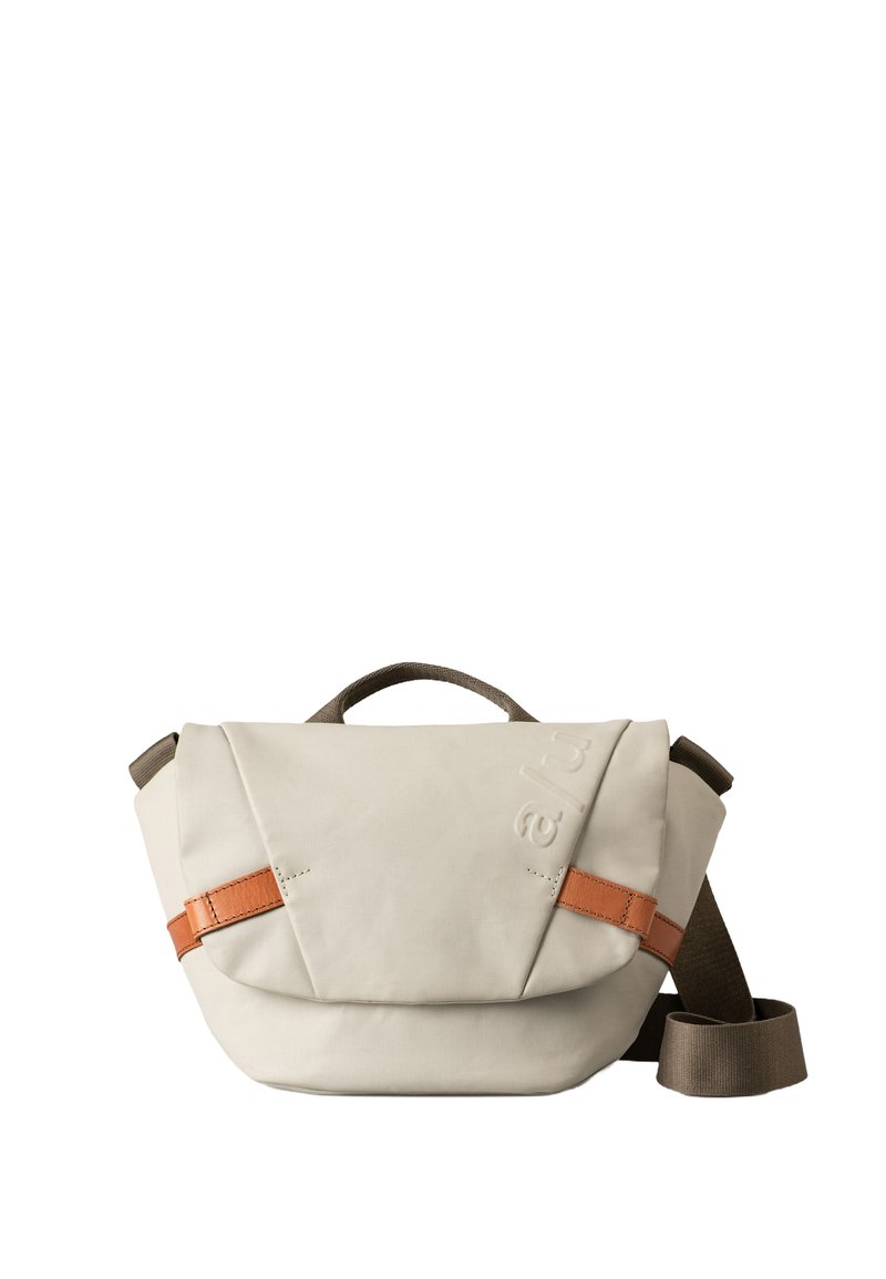 Beige Schultertasche aus robustem Stoff mit einem braunen Lederakzentriemen. Verfügt über eine strukturierte Form und einen oberen Griff zum Tragen.