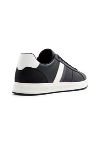 Sneaker in pelle nera con una striscia bianca e un cappuccio del tallone bianco. Caratterizzato da una suola in gomma e design con lacci. Presenta pannelli testurizzati.
