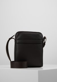Borsa a tracolla nera in pelle con una texture liscia, chiusura a zip e tracolla regolabile. Presenta una tasca frontale e una forma rettangolare.