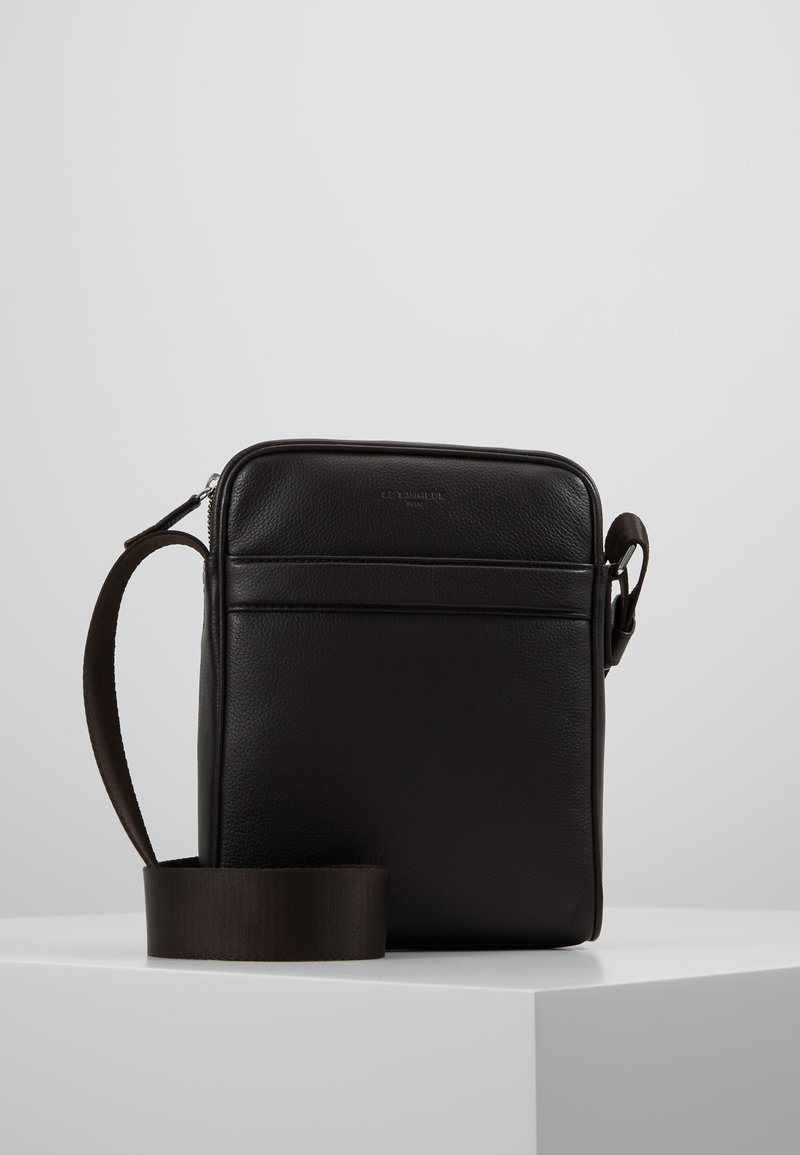 Borsa a tracolla nera in pelle con una texture liscia, chiusura a zip e tracolla regolabile. Presenta una tasca frontale e una forma rettangolare.