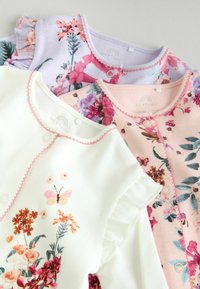 Tre cardigan per bambini: bianco con stampa floreale, rosa con design floreale e lavanda con maniche a volant. Tessuto morbido, motivi colorati.