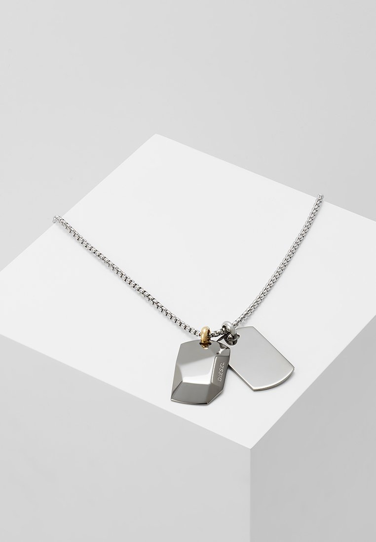 Sølv halskæde med geometriske mærker i poleret metal, et med et logo. Inkluderer en kæde med et guld aksentled.