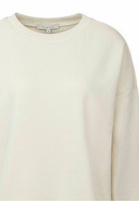 Light beige sweatshirt with a round neckline, dropped shoulder seams, and a soft texture. Brand label "bugatti" visible inside the collar.