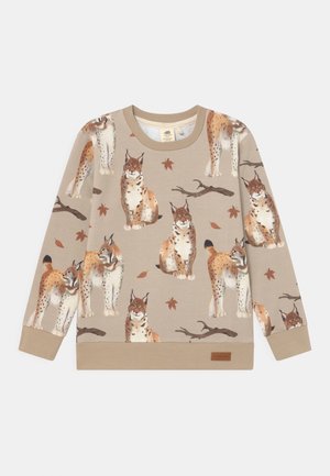 Sweat-shirt beige clair avec un motif de lynx et des feuilles éparpillées. Col et poignets côtelés, texture douce, avec une petite étiquette marron à l'ourlet.