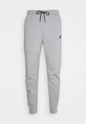 Pantaloni grigi in felpa morbida, dotati di una vita con cordino, gambe affusolate, tasche laterali e un piccolo logo nero sulla coscia sinistra.