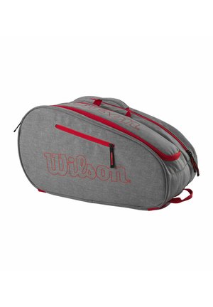 Grijze Wilson tennistas met rode ritsen en handvatten, twee hoofdvakken en een voorvak met rits, op een witte achtergrond.
