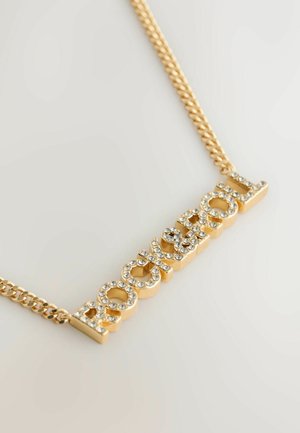 Złocony naszyjnik z wyrazem "ROCK" w wyraźnych literach, zdobiony przezroczystymi cyrkoniami. Skręcony wzór łańcuszka dodaje tekstury.