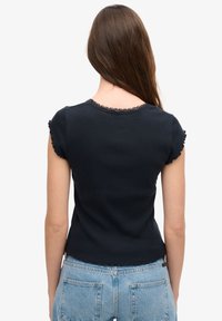 Mørkeblå ribbet t-shirt med korte flæseærmer og scallop-udskæring, der har en tætsiddende pasform og let cropped kant.