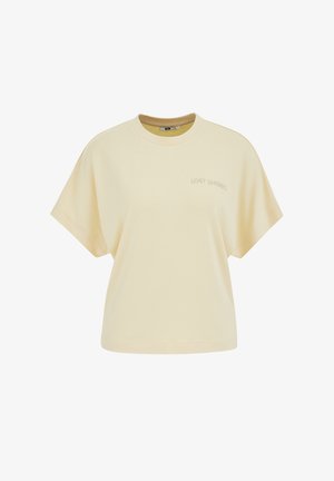 Világos bézs színű, rövid ujjú, kerek nyakú póló laza szabással, kis "LOST SHORES" felirattal a bal mellrészen.