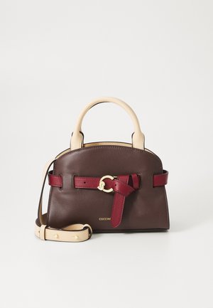 Brown leather handbag with cream top handles, burgundy accents, and gold hardware. Features a removable strap and a tied detail on the front.