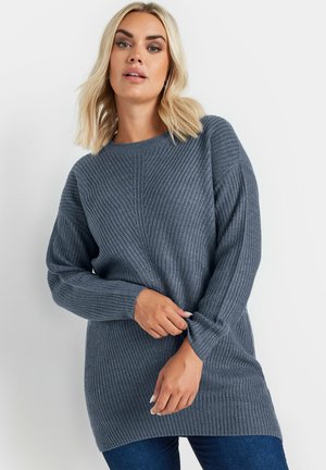 Pull en tricot gris à manches longues, texture côtelée et encolure ronde ; présente une coupe décontractée et un ourlet arrière plus long.