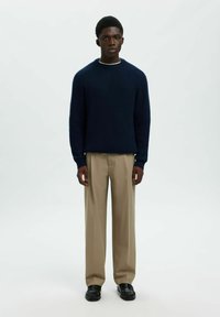 Jūras spēku ribota adījuma džemperis ar garām piedurknēm un apaļu kakla izgriezumu; saskaņots ar beigām platiem biksēm un melnām kurpēm. Vienkāršs, teksturēts dizains.