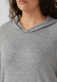 Lichtgrijze hoodie van zachte stof met een v-hals en een gevoerde capuchon, met raglanmouwen en een subtiele textuur.