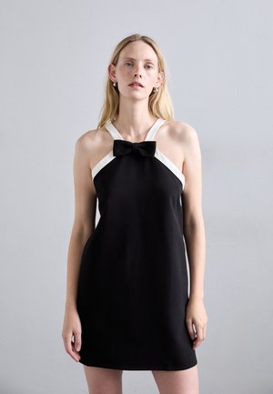 Vestido negro sin mangas con acentos blancos y un detalle de lazo en la parte frontal. Tela suave, silueta ajustada y diseño hasta la rodilla.