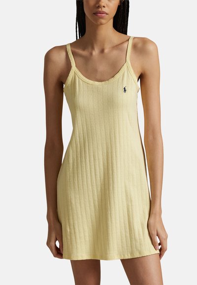 Yellow ribbed tank dress with thin straps, featuring a scalloped neckline and a small logo on the chest. Soft cotton texture.