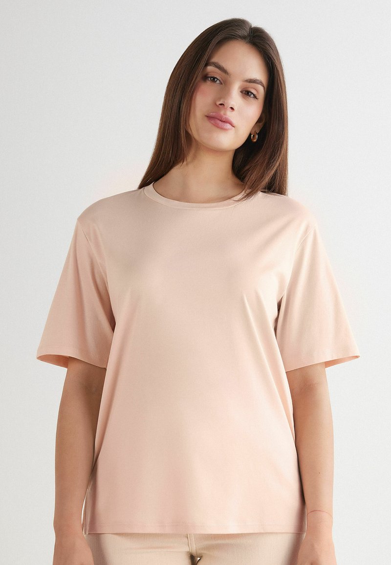 T-shirt a maniche corte, di colore rosa chiaro, realizzata in tessuto morbido, con scollatura rotonda e vestibilità comoda, caratterizzata da un design semplice e senza motivi visibili.