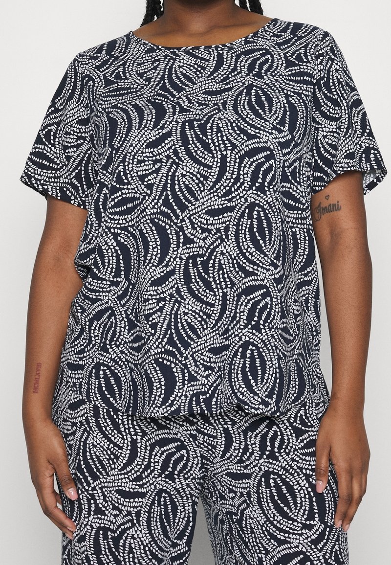 Mörkblå kortärmad topp med ett vitt abstrakt mönster. Mjuk textil med en avslappnad passform, rund halsringning och flödande design.