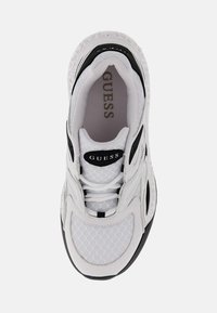 Sneaker Guess bianca e nera con tessuto in rete, linguetta imbottita e suola spessa, vista dall'alto che mostra il nome del marchio all'interno.