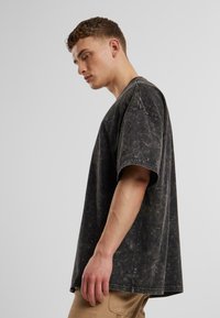 Sort, oversized t-shirt med en tekstureret, falmet finish. Har korte ærmer og rund halsudskæring. Casual design, stoffet ser blødt ud.